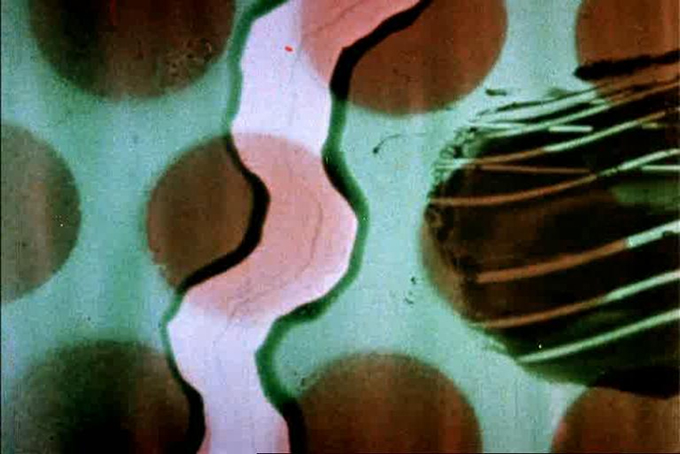 A still from A Colour Box, a 1935 film by artist Len Lye, depicting a pale blue background, large brown red dots evenly spaced in three rows, and a white wavy line running vertically through - all hand-painted on a strip of film.