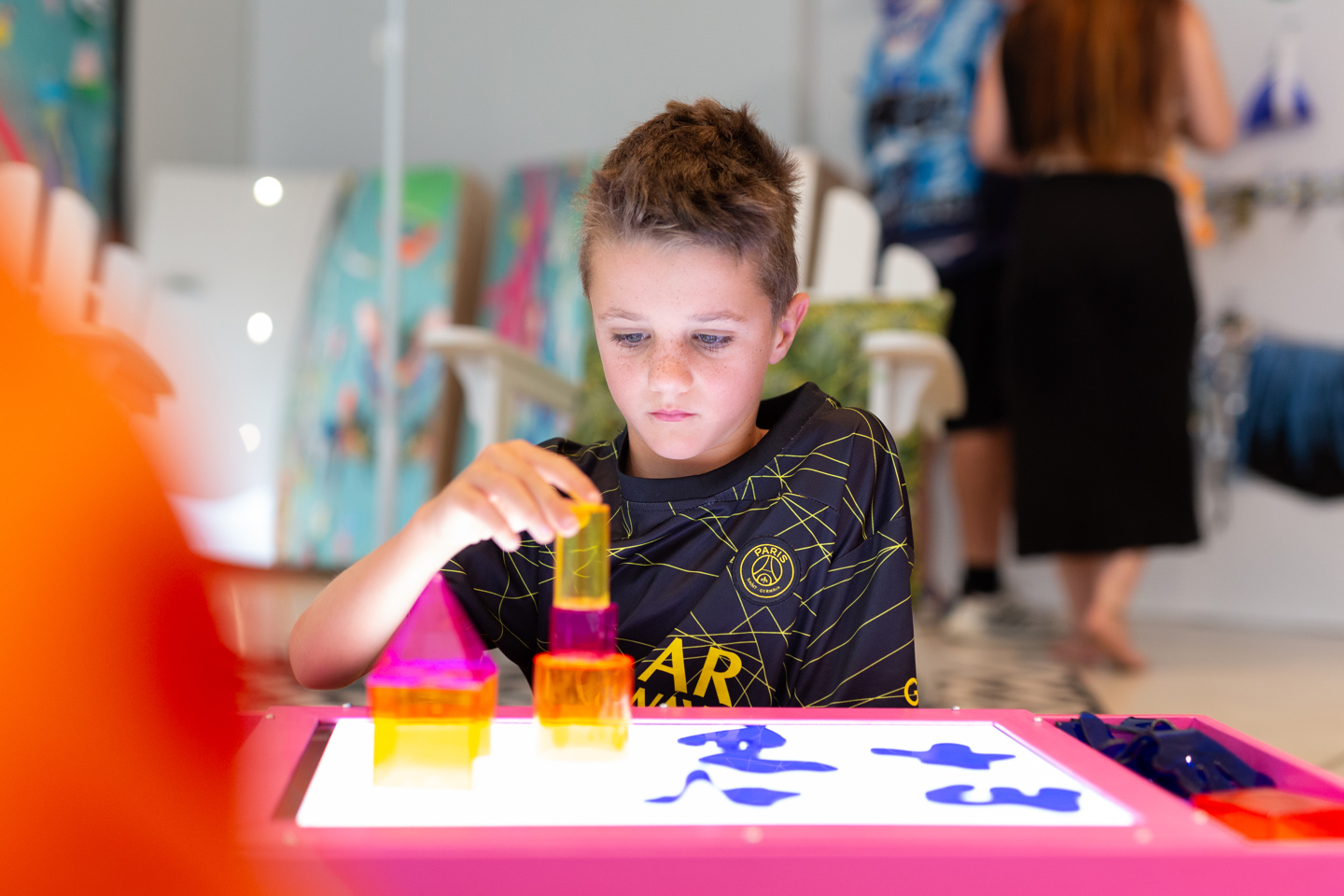 Child stacking coloured blocks on light box