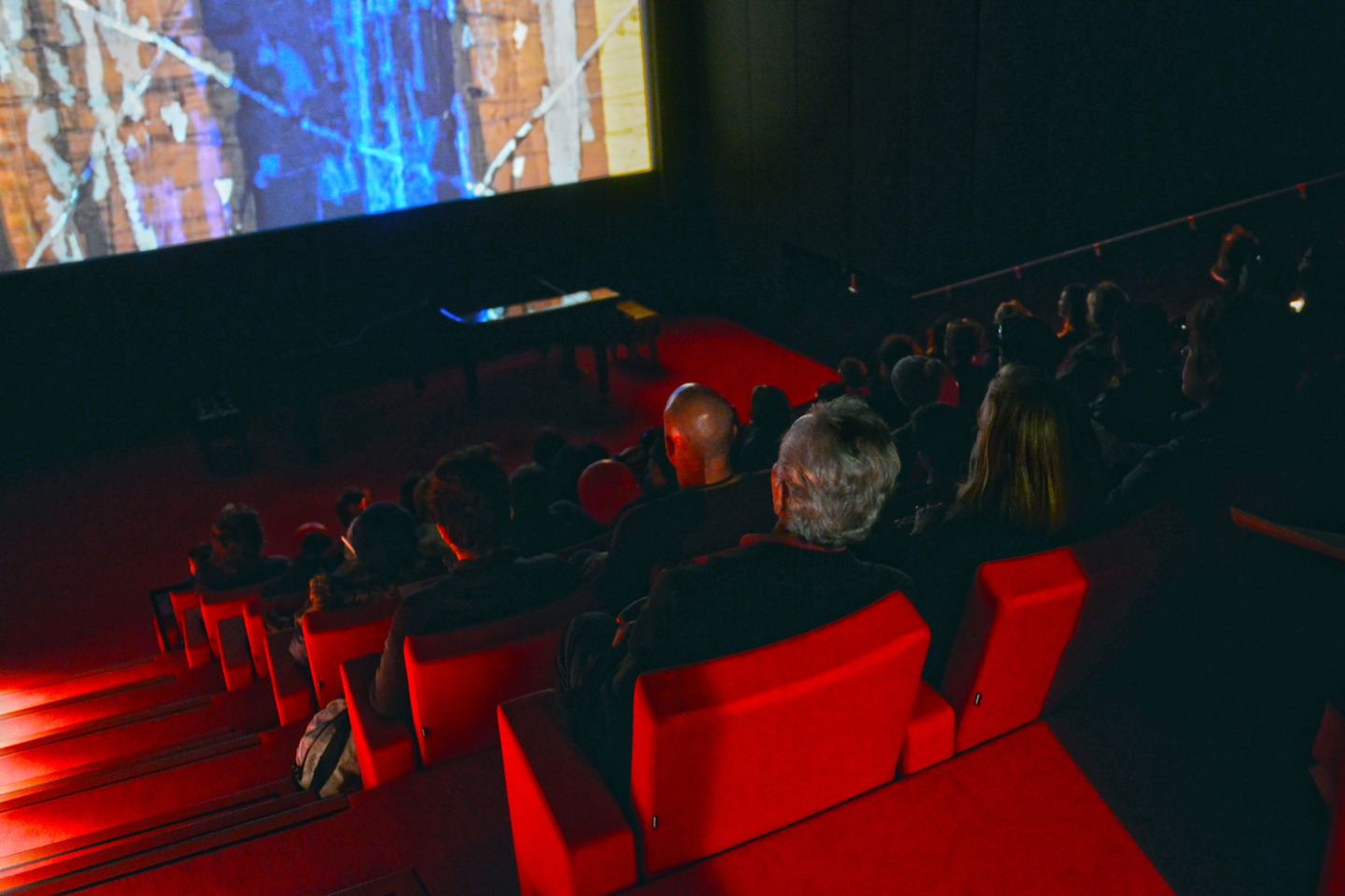Visitors watch a film screening in the darkened Len Lye Centre Cinema, which is characterised by its vibrant red seats and carpet. Photo by Pip Guthrie. 